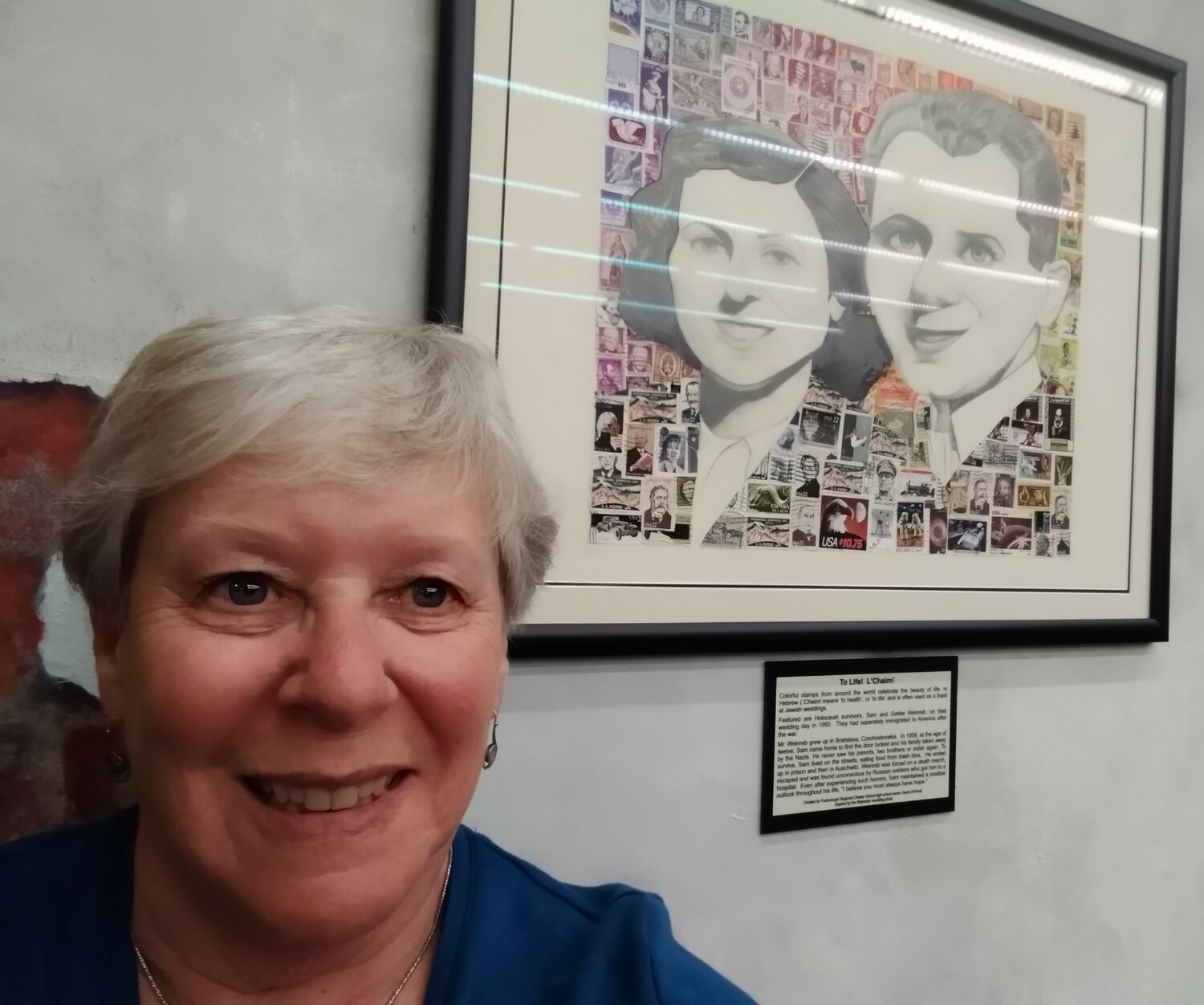 Charlotte Sheer took this selfie in front of one of the 18 collages made from some of the 11 million stamps collected as part of the Holocaust Stamps Project that’s part of the exhibit at the American Philatelic Center called “A Philatelic Memorial of the Holocaust.” “L’Chaim – To Life!” celebrates Holocaust survivors Sam and Goldie Weinreb.